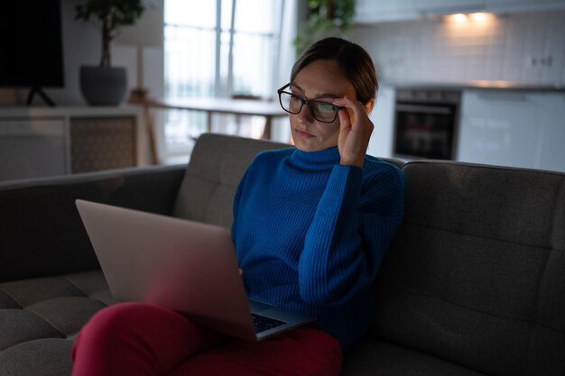 La donna pensierosa e immotivata guarda lo schermo svolge compiti freelance remoti a casa sentendo mancanza di energia