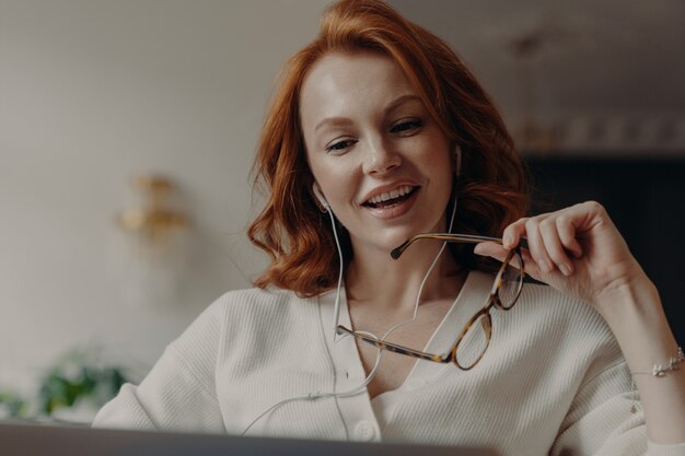 La donna piacevole rossa sicura si è concentrata in computer portatile