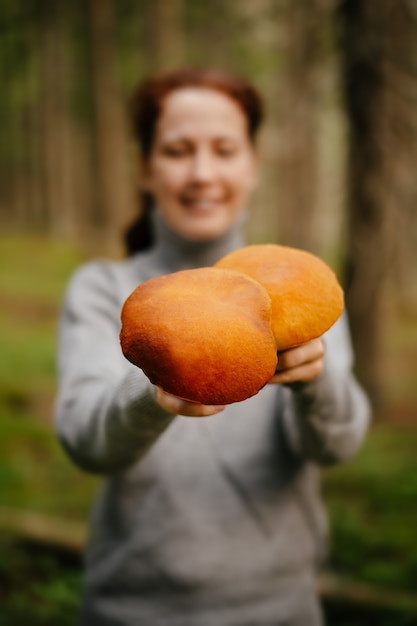 La donna porge funghi commestibili selvatici alla telecamera il concetto di cibo sano e prodotti biologici