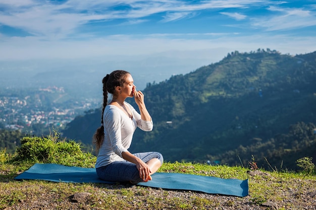 La donna pratica il controllo del respiro del pranayama yoga nella posa del loto padmasana all'aperto in Himalaya