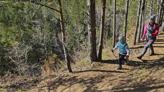 La donna pratica il nordic walking nella natura Ragazze e bambini usano bastoncini da trekking e zaino per bastoncini nordici