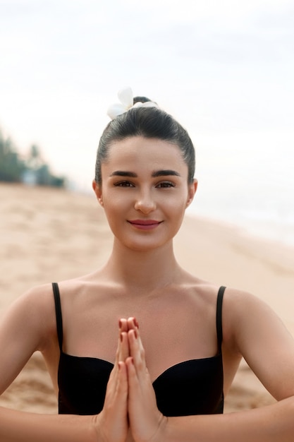 La donna pratica lo yoga e medita nella posizione del loto sulla spiaggia. Bella ragazza che fa yoga.