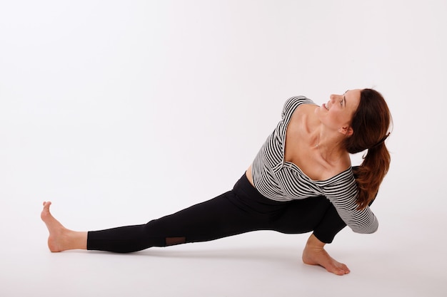la donna pratica yoga in leggings neri su uno sfondo bianco isolato. giornata internazionale dello yoga