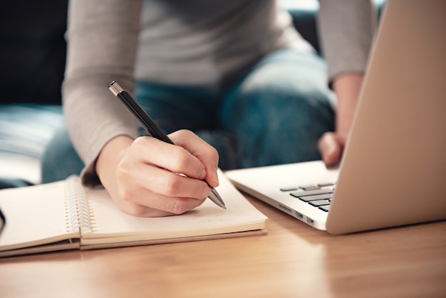 La donna prende appunti seduto alla scrivania mentre studia online.