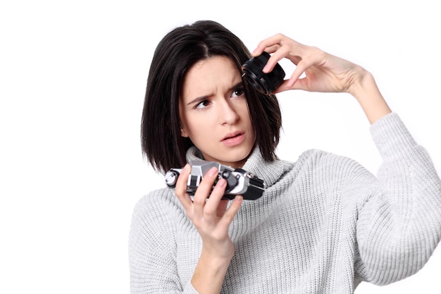 La donna prende le immagini tenendo la macchina fotografica isolata su un bianco