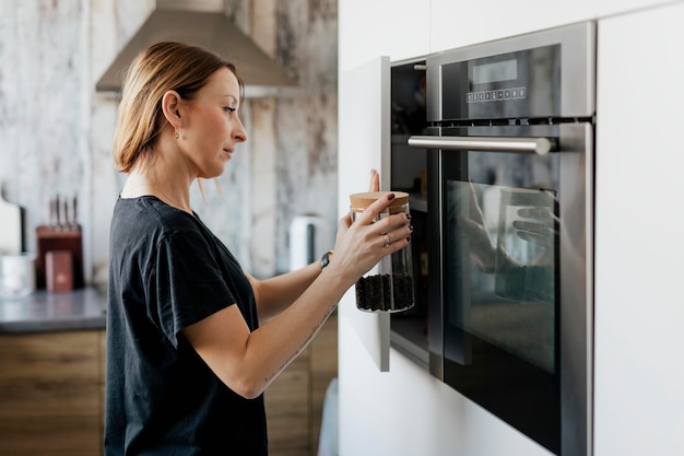 La donna prende un barattolo di chicchi di caffè dalla credenza della sua cucina