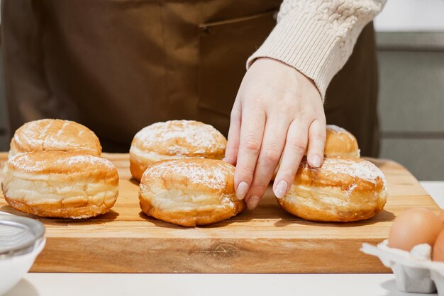 La donna prepara le ciambelle fresche con marmellata nella cucina domestica Cucinare il tradizionale sufganiyot ebraico di Hanukkah