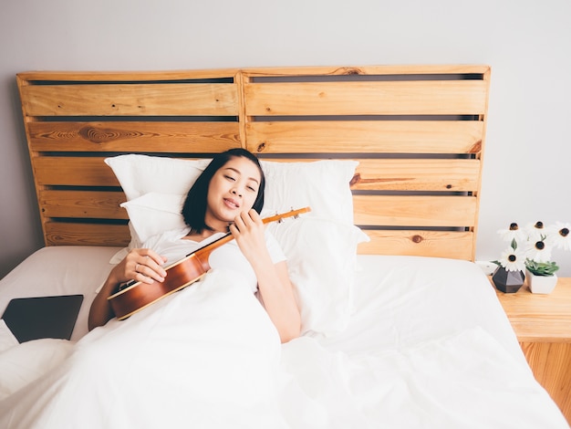 La donna prova ad imparare l&#39;ukulele nella sua camera da letto.