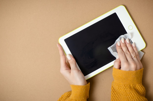 La donna pulisce la compressa bianca, la disinfezione del gadget mentre il virus. Ministero degli interni mentre auto-isolamento, lavoro da casa. Formazione online, e-learning durante la quarantena.