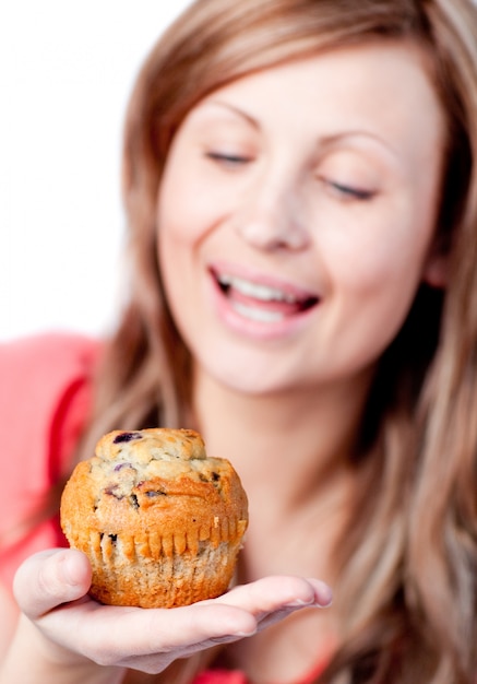 La donna radiosa sta mangiando un muffin