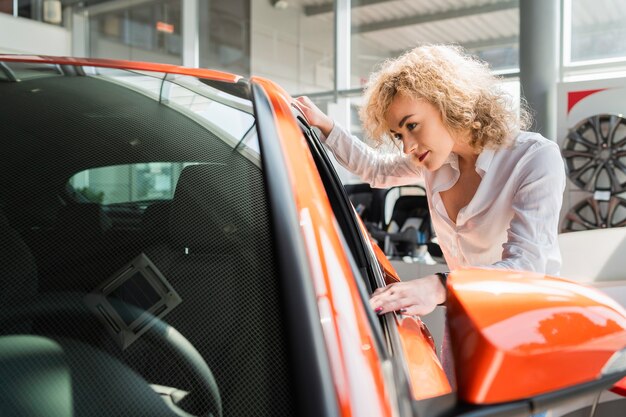 La donna riccia guarda l'auto in concessionaria