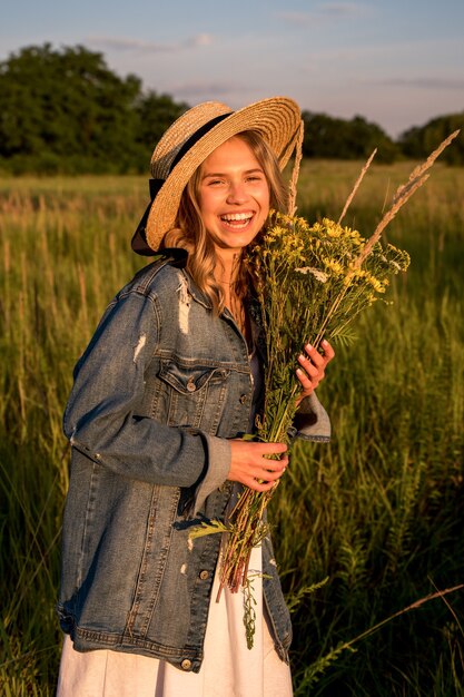 La donna ride e tiene in mano un mazzo di fiori di campo