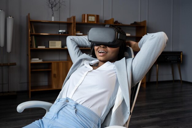 La donna rilassata indossa le cuffie con occhiali vr sedersi alla scrivania dell'ufficio sperimentando l'innovativa realtà virtuale