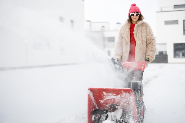 La donna rimuove la neve con una macchina spazzaneve vicino a casa