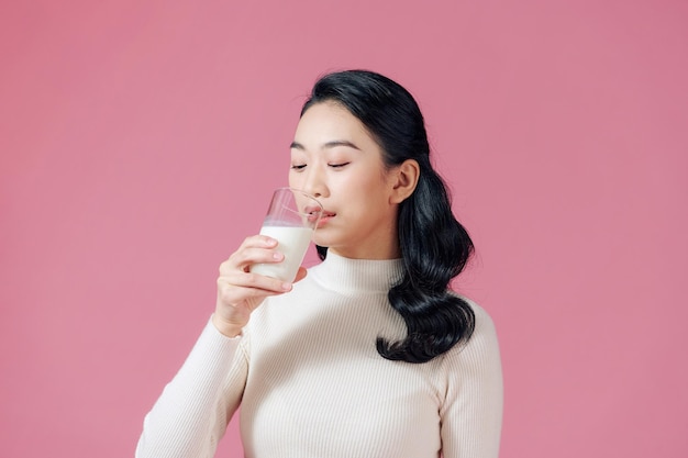 La donna sana sveglia sta bevendo il latte da un vetro isolato su fondo rosa