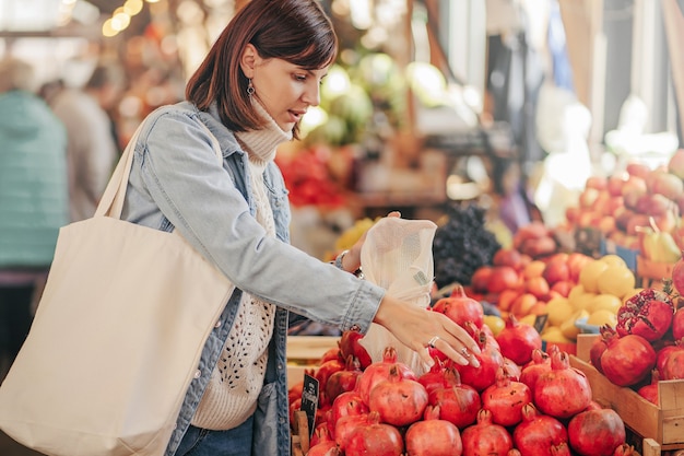 La donna sceglie frutta e verdura al mercato alimentare. Borsa ecologica riutilizzabile per lo shopping. Stile di vita sostenibile. Concetto ecologico.