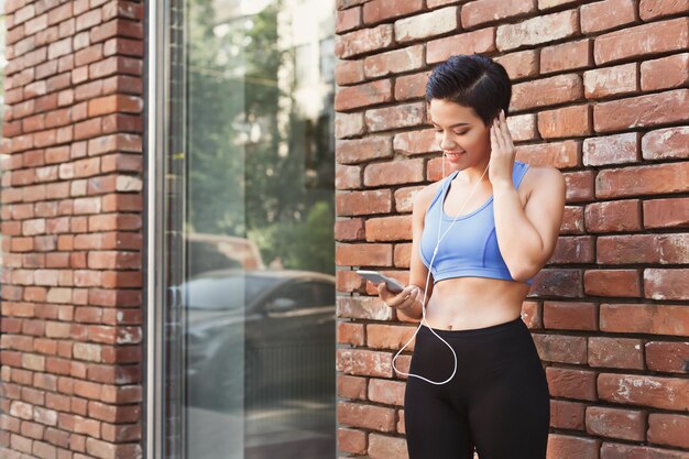 La donna sceglie la musica da ascoltare nel suo telefono cellulare durante il jogging in città, copia lo spazio