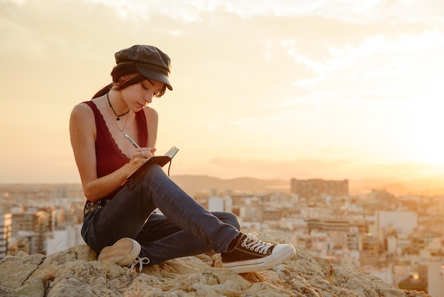 La donna scrive nel suo taccuino frasi e pensieri all'aperto al tramonto