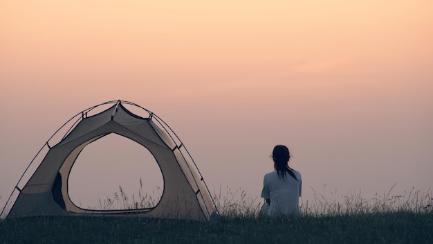 La donna seduta vicino alla tenda del campeggio sullo sfondo del bellissimo cielo