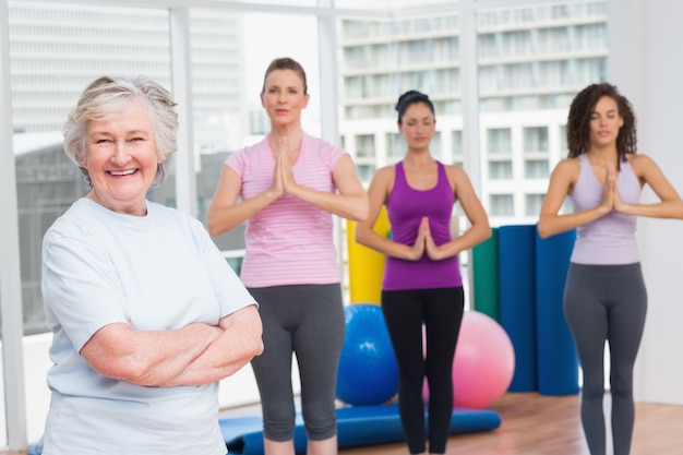 La donna senior con le armi ha attraversato la condizione nella palestra