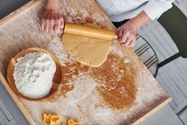 La donna senior cucina i biscotti di Natale sulla cucina durante il giorno