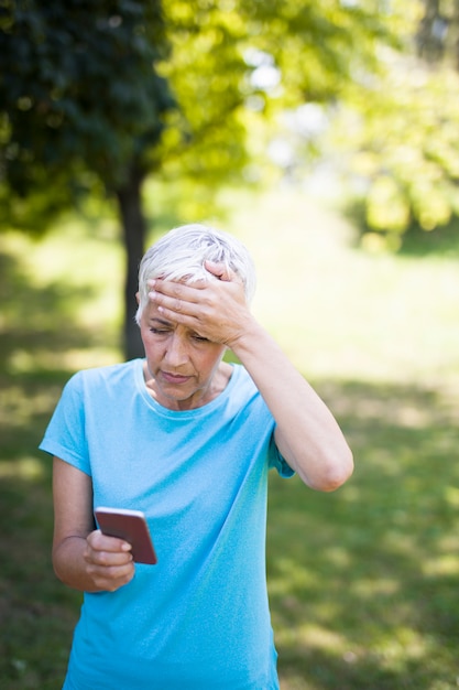 La donna senior preoccupata legge un messaggio su un telefono cellulare