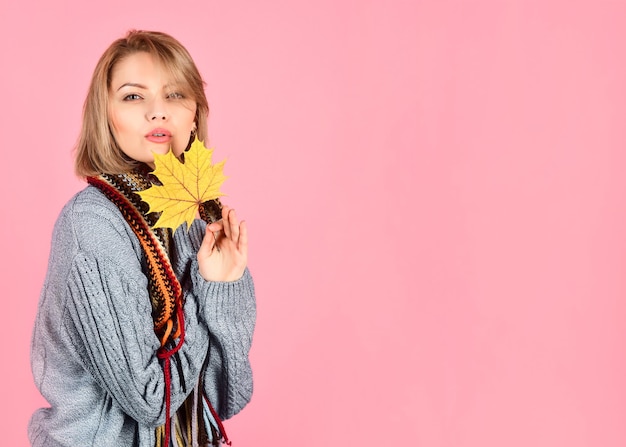 La donna sensuale tiene la donna della foglia d'acero in un maglione caldo tiene la donna della foglia d'oro con l'autunno delle foglie d'autunno