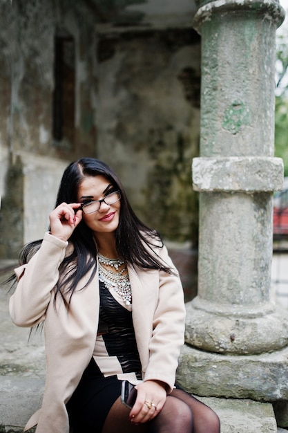 La donna sexy dei capelli neri in vetri e cappotto ha proposto alla via di vecchia città.