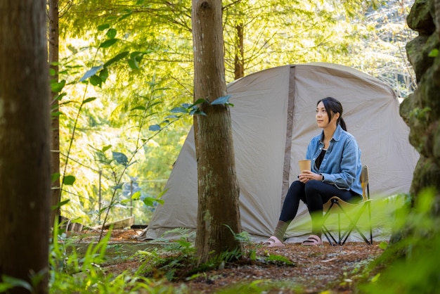 La donna si diverte ad andare in campeggio nella foresta
