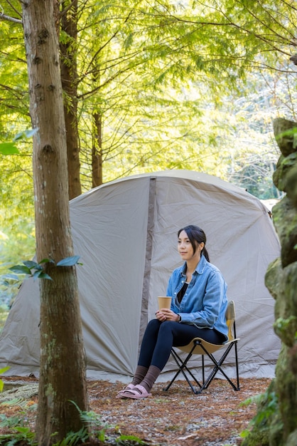 La donna si diverte ad andare in campeggio nella foresta