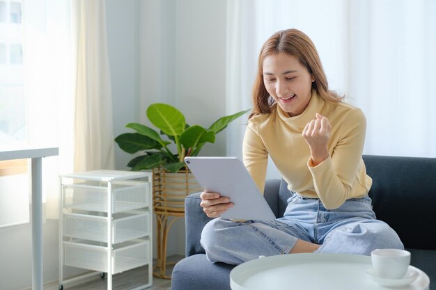 La donna si diverte con l'applicazione di social media di contenuti su tablet digitale seduto sul divano di casa