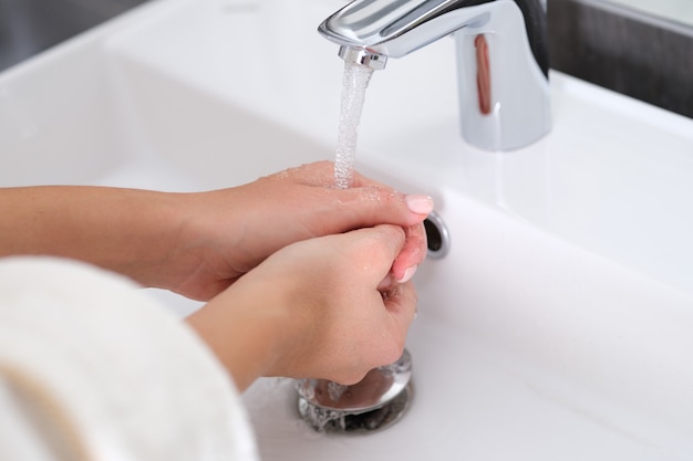 La donna si lava le mani con acqua pulita del rubinetto