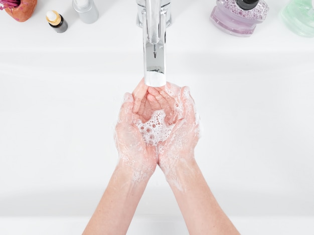 La donna si lava le mani sotto un rubinetto. Concetto di igiene, vista dall'alto, assistenza sanitaria. Igiene personale e cura del corpo
