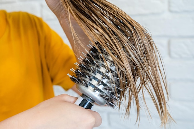 La donna si pettina i capelli bagnati Spazzolatura dei capelli