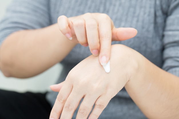 La donna si prende cura della mano usando la crema cosmetica