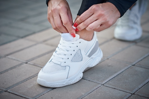 La donna si prepara per la corsa. Mani femminili che lega i lacci delle scarpe su una sneaker sportiva