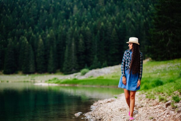 La donna si rilassa nella pineta e nel lago. Capelli lunghi donna viaggio Lago di montagna.