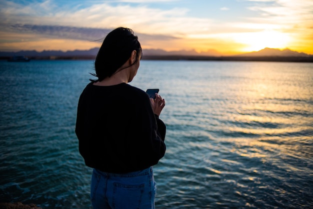 La donna si rilassa sul mare al tramonto