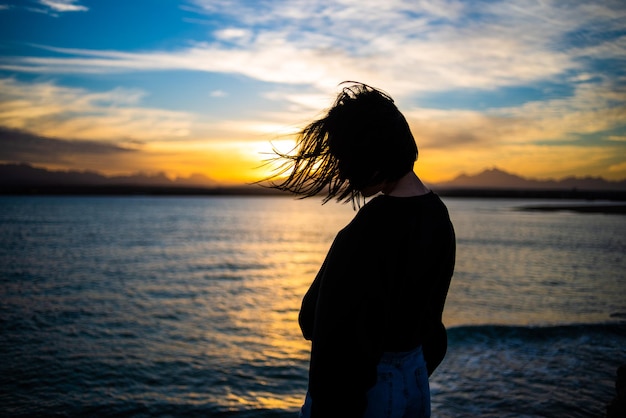 La donna si rilassa sul mare al tramonto