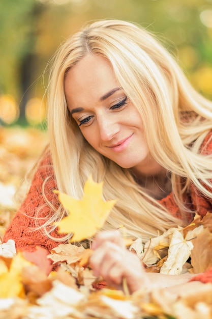 La donna si riposa sulle foglie al parco di autunno