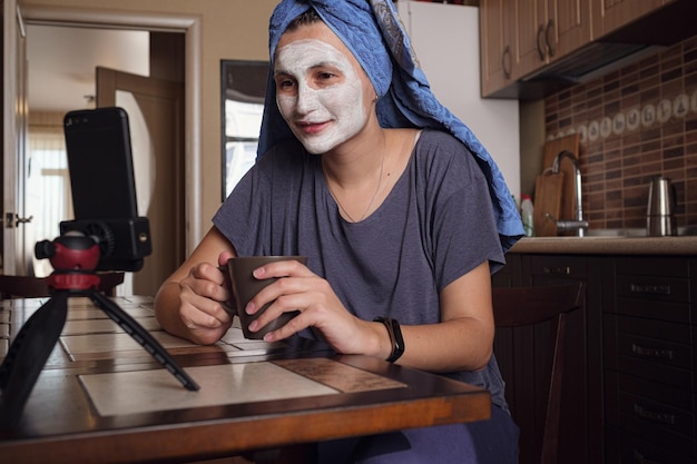 La donna si siede sulla cucina e fa una maschera di argilla verde