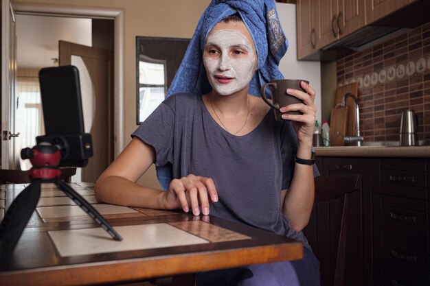 La donna si siede sulla cucina e fa una maschera di argilla verde