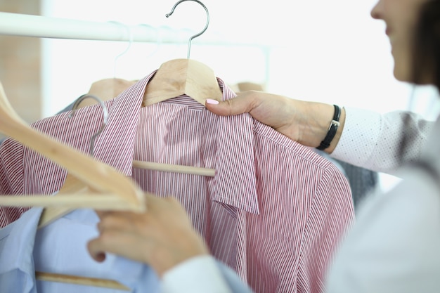 La donna si toglie e tiene in mano grucce con camicie