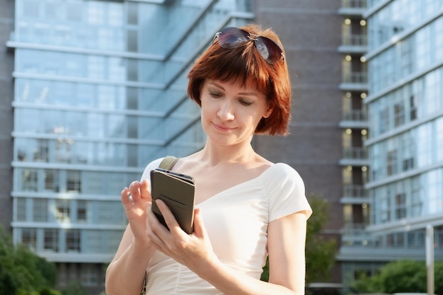 La donna si trova in un quartiere di una città d'affari e guarda lo schermo dello smartphone