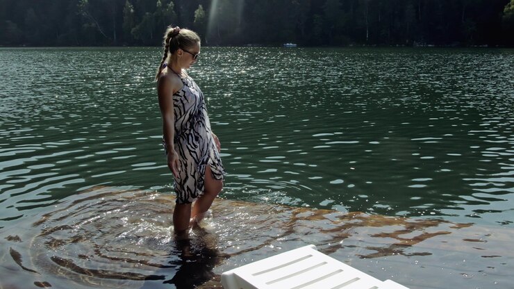 Foto la donna si trova su un lettino con occhiali da sole e uno scialle di seta boho la ragazza riposa su un molo sottomarino di legno inondato il marciapiede è coperto di acqua nel lago