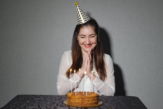 La donna sola celebra una vacanza, si siede da solo a un tavolo con una torta e candele, primo piano