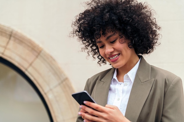 La donna sorride felice digitando il messaggio con il suo telefono