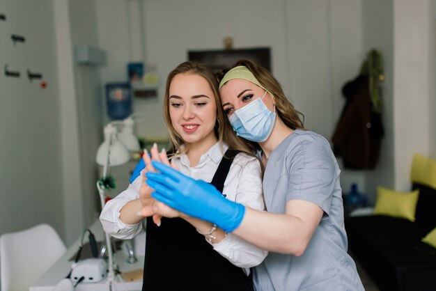 La donna sorridente al salone di bellezza ha una manicure dal maestro di manicure. Il maestro sta usando una lima per unghie.