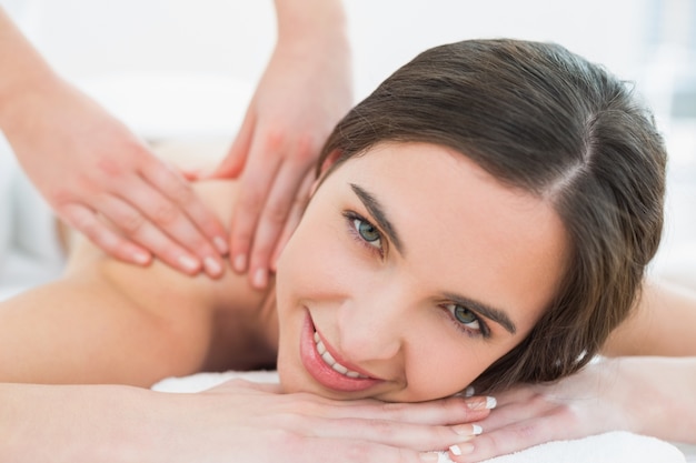 La donna sorridente che gode della spalla massaggia alla stazione termale di bellezza