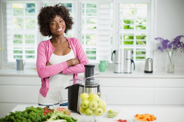 La donna sorridente che sta con le armi ha attraversato in cucina